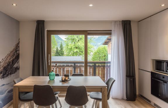 A dining room with a wooden table and chairs and a view of the mountains.