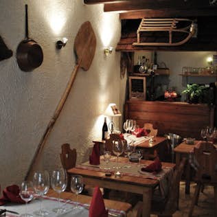 Cozy restaurant interior with rustic wooden furnishings, tables set with glassware and red napkins, and vintage decor including a large paddle hanging on the wall.