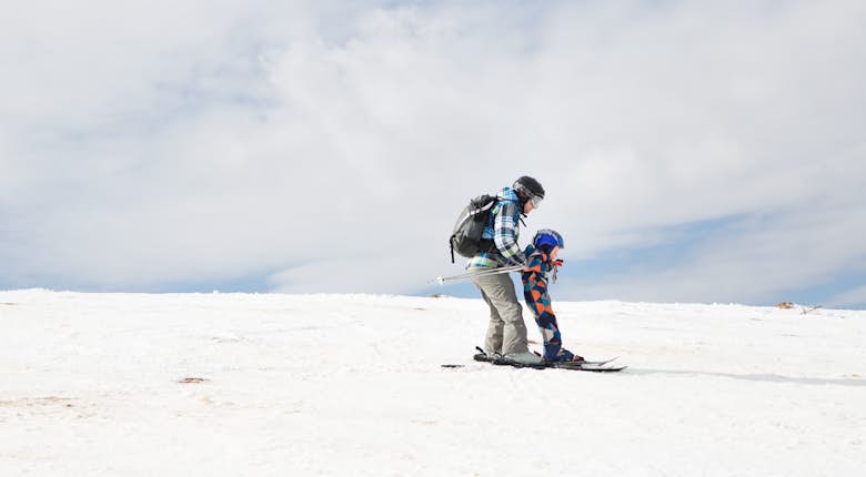 A man and a child on skis on a snowy hill.