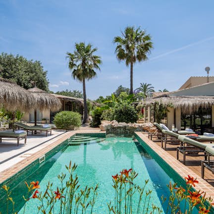 A swimming pool with lounge chairs and thatched umbrellas.