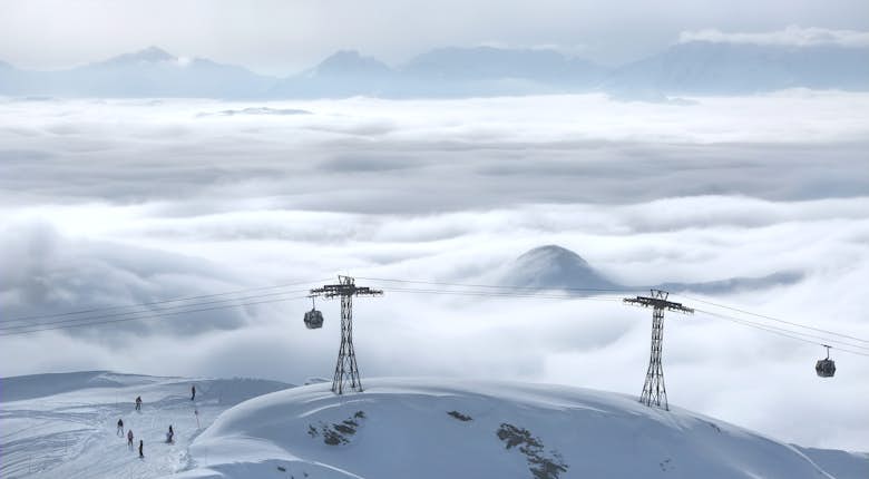 Gondolas and skiers on a snow covered mountain.