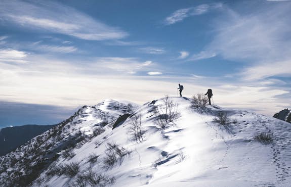 Two people standing on top of a snow covered mountain