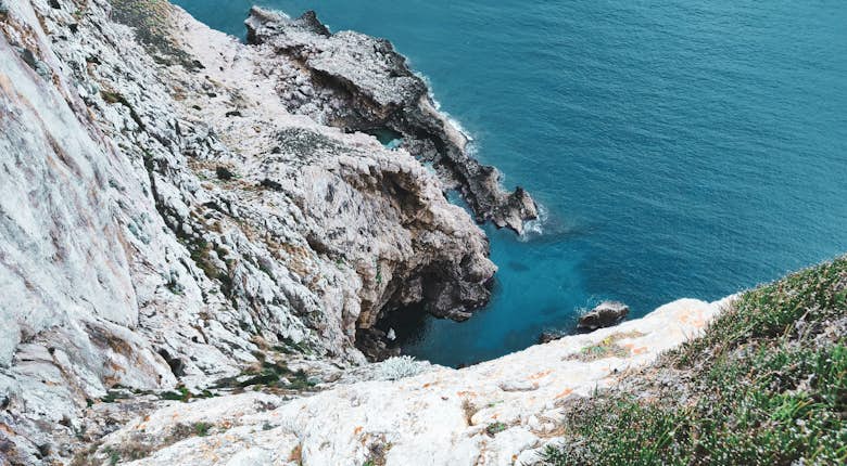 A person is standing on a cliff overlooking the ocean.