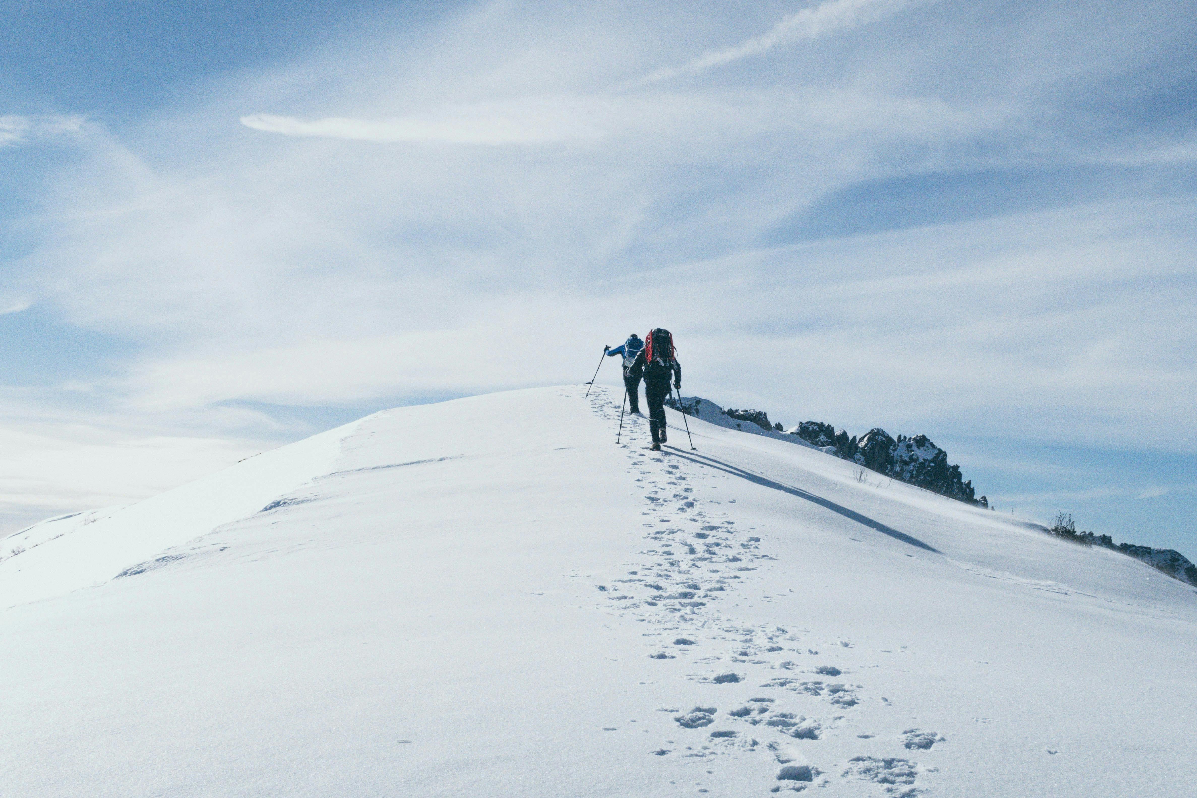 A person on skis walking up a snow covered hill.