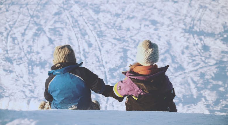 Two kids on top of a snowy hill