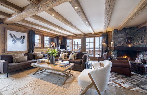 A living room with wooden beams and a fireplace.