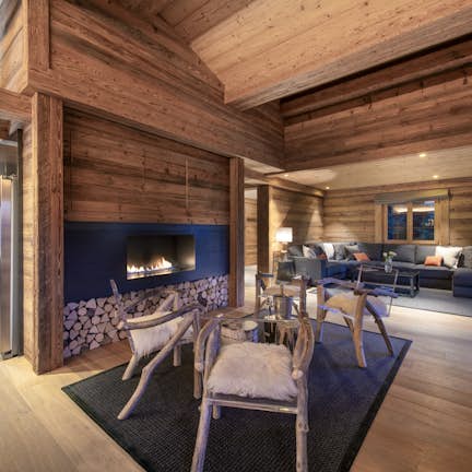 A living room with wood walls and a fireplace.