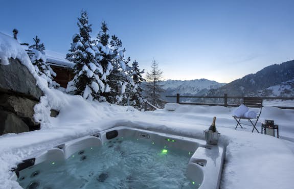 A hot tub surrounded by snow and trees.