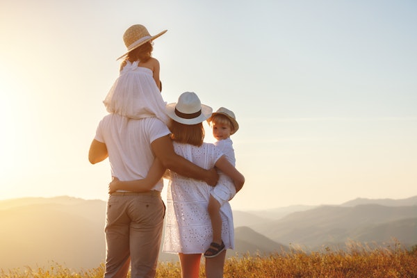 Une famille de quatre personnes regardant le paysage de montagne debout ensemble