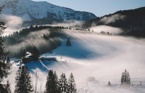 A mountain covered in snow with fog in the background.