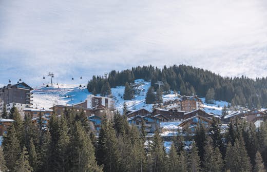 Mountain resort with chalets and ski lifts under a clear blue sky.