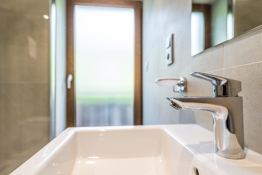 Morzine location - Appartement Kauri - Evier blanc dans une salle de bain moderne avec une douche à l'italienne dans l'appartement familial Kauri à Morzine