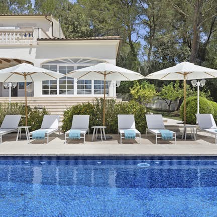 Sun loungers in front of swimming pool in a luxury villa in Mallorca.