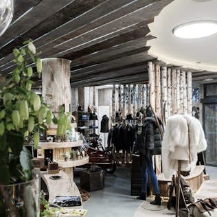 Interior of a rustic-style boutique displaying various clothing items, accessories, and decorative wood elements.