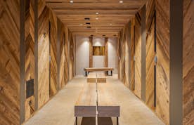 Méribel  - 6 Méribel location - Appartement Nuna - Wood-paneled hallway with benches, featuring chevron-patterned walls, recessed lighting, and a textured wall at the end.