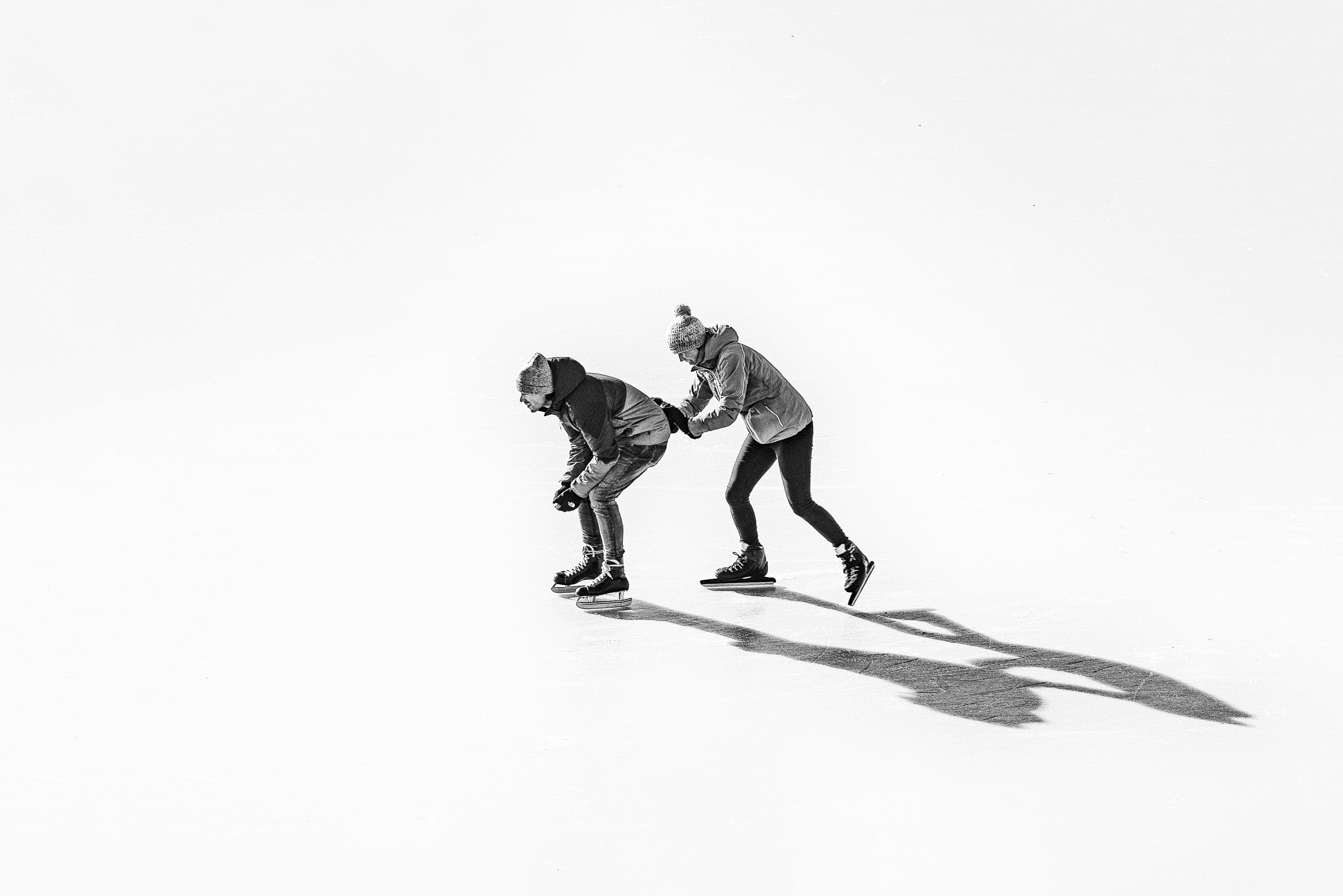 Black and white photo of two people skating on the ice.