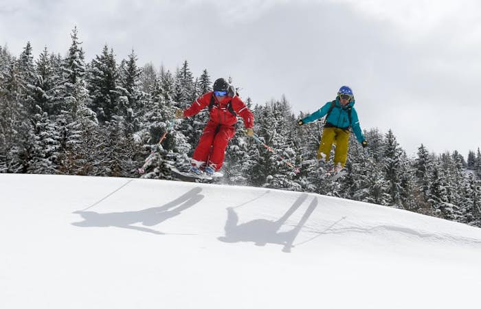 Deux personnes en tenue d'hiver pratiquant une activité de raquettes à neige aux Arcs